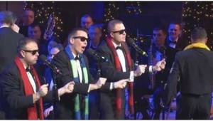 United States Navy Band zpívají vánoční klasiku a poté se k nim přidá muž se žlu